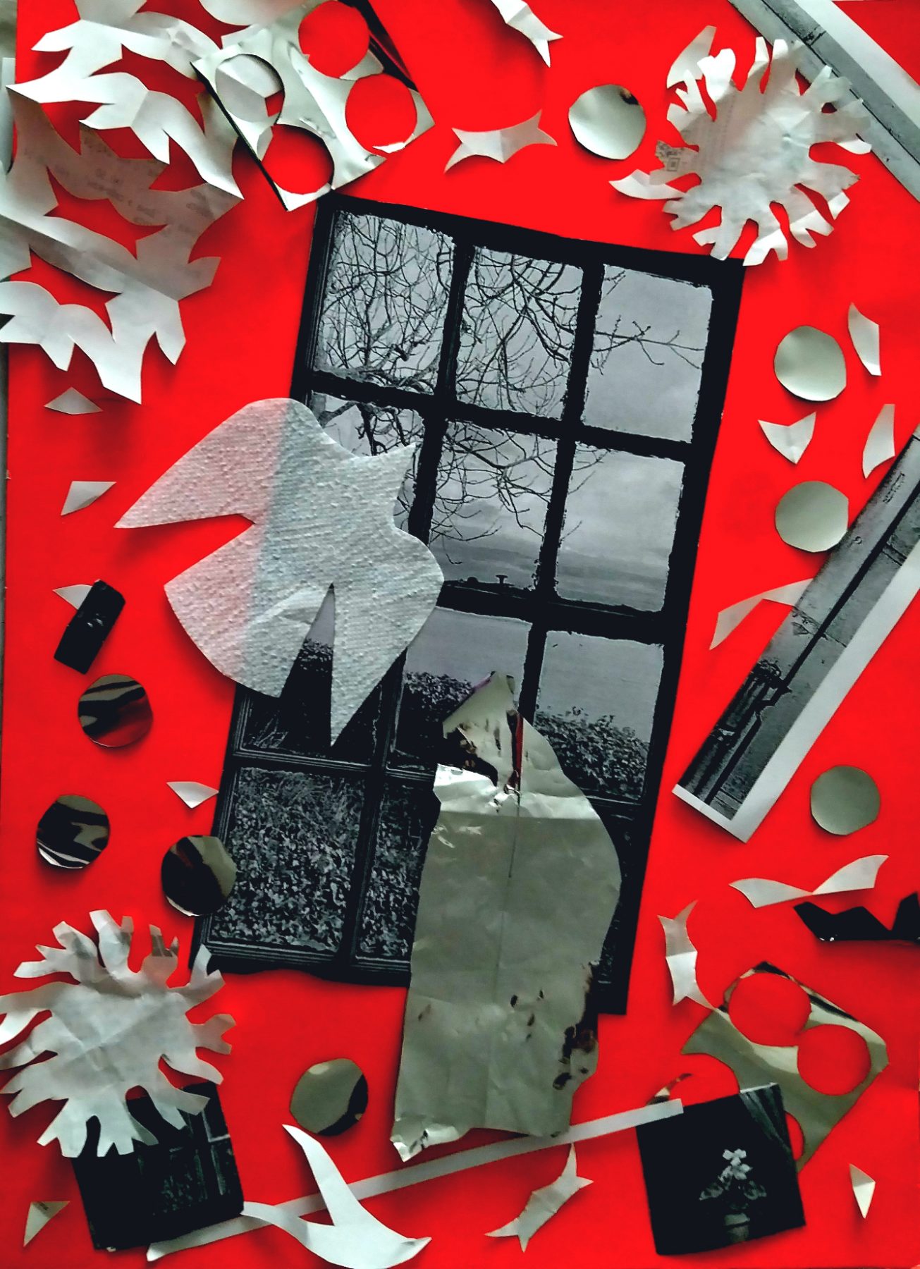 A scarlet ground. A black-framed sash window, its upper panes showing bare winter branches against a white sky, its lower panes a dark hedge. A large embossed paper-napkin figure, cut with jagged limbs, hangs across the glass; a crumpled sheet of foil falls below it. Punched circles and torn napkin birds scatter across the red, with two strips of black-and-white photograph at the right edge.